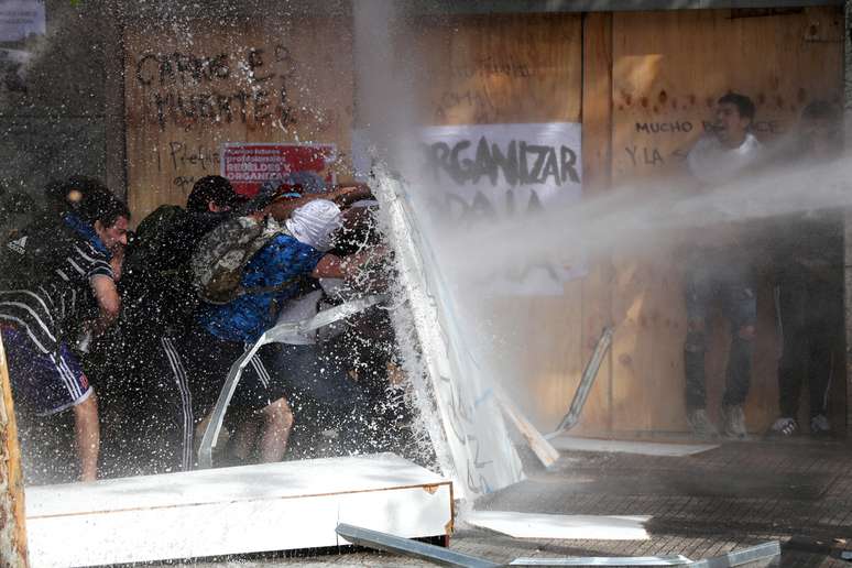 Manifestantes se protegem de jato d'água lançado pela polícia em Santiago
22/10/2019
REUTERS/Ivan Alvarado
