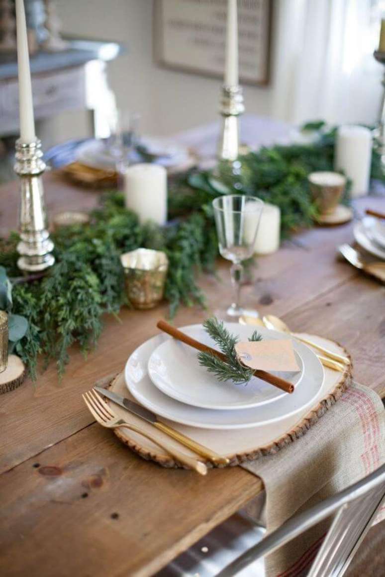 21. Decoração de mesa de natal simples com plantas e castiçais prateadas – Por: The Spruce