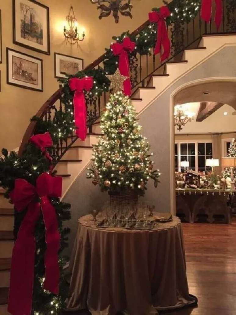 43. Decoração natalina para casas clássicas com laços vermelhos e pisca pisca na escada – Foto: Top Interiors Design