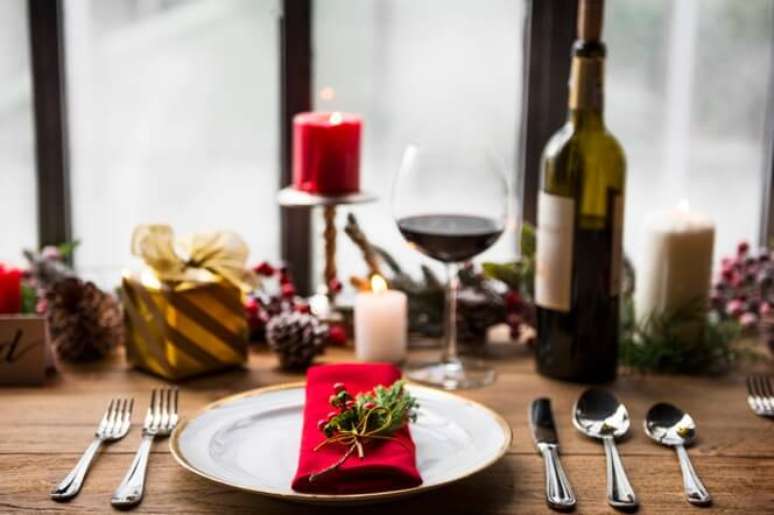 3. Mesa de natal com guardanapo vermelho, taça de vinho e velas – Por: Freepik