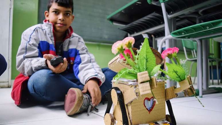 Guilherme e seu Wall-e, personagem que tenta salvar as flores em um mundo cheio de lixo; na versão de papelão, ele carrega flores emprestadas pela diretora