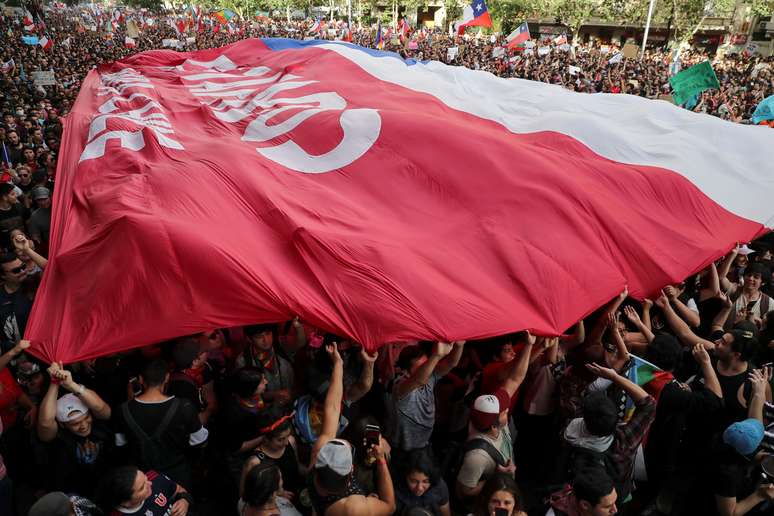 Manifestantes carregam bandeira gigante do Chile durante protestos em Santiago
25/10/2019 REUTERS/Ivan Alvarado 