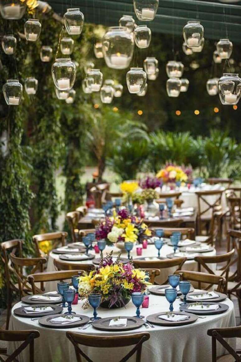 64. Decora&ccedil;&atilde;o de casamento no campo com velas suspensas e arranjos de flores nas mesas dos convidados &ndash; Foto: Luxury Wedding