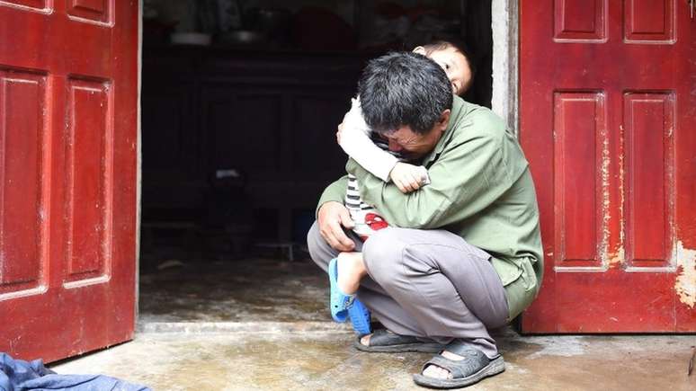 Le Minh Tuan abraça seu neto. Ele espera que seu filho não esteja entre os mortos.
