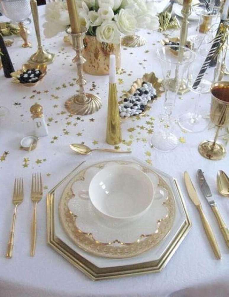 6. Decoração mesa réveillon branca e dourada com estrelinhas na mesa e arranjo de flores brancas – Foto: Design Innova
