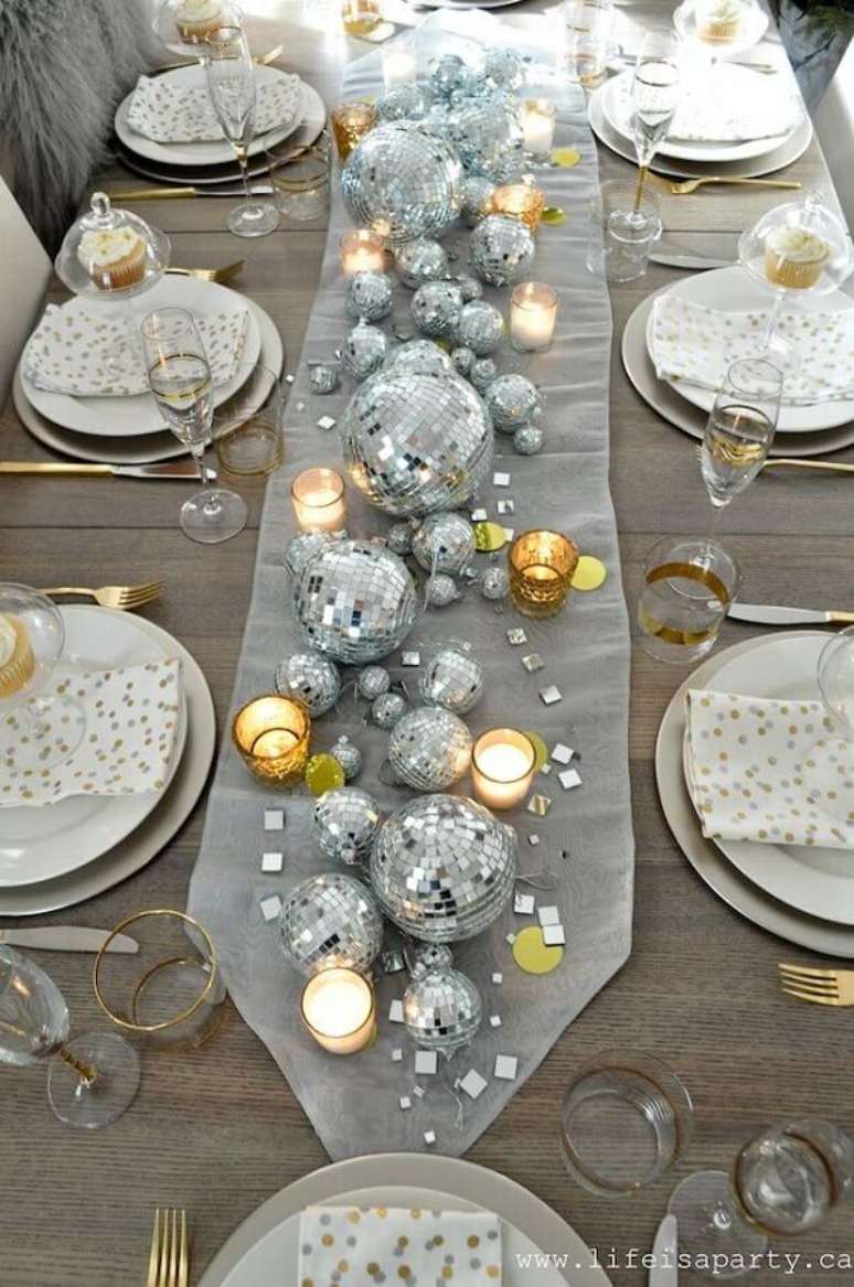 42. Decoração mesa réveillon simples com velas e bolas prateadas de vários tamanhos – Foto: Life is Party
