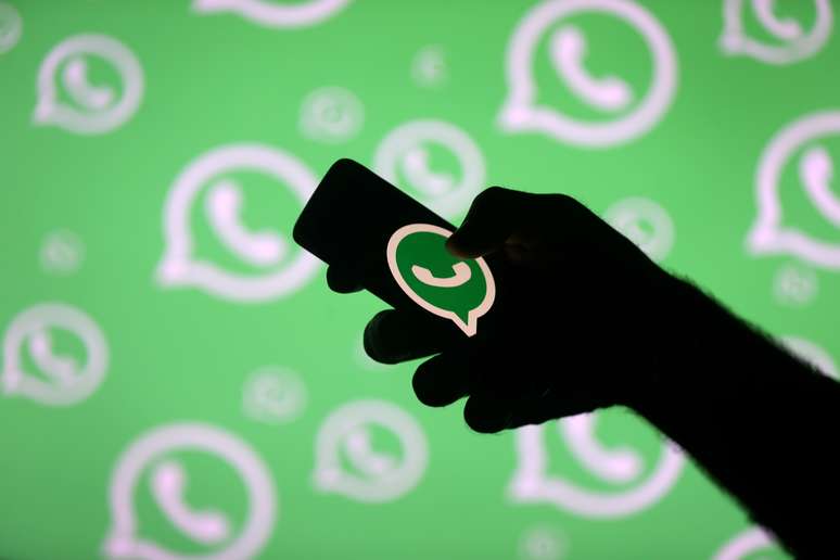 Homem manuseia celular em frente a uma ilustra&ccedil;&atilde;o com logotipos do Whatsapp. 14/9/2017. REUTERS/Dado Ruvic