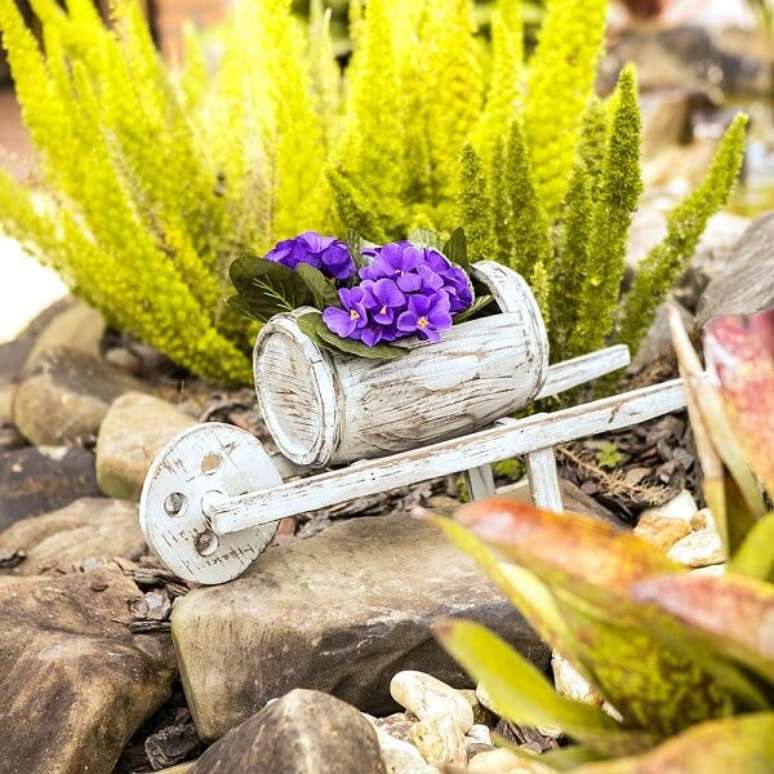 16. Invista em enfeites para jardim em tamanho miniatura como esse carrinho de mão barril. Fonte: Carro de Mola