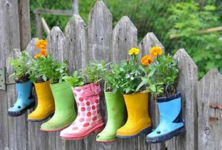 74. Enfeites para jardim feitos com botas fixadas na parede de madeira. Fonte: Pinterest
