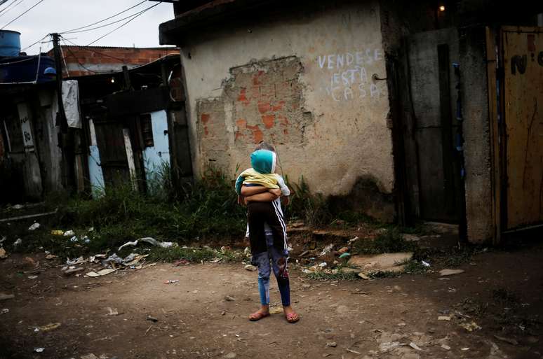 A girl holds her brother at the entrance of their house at a favela, or a slum, in Rio de Janeiro, Brazil June 24, 2016. Picture taken June 24, 2016. REUTERS/Nacho Doce - RC1EE125CC30