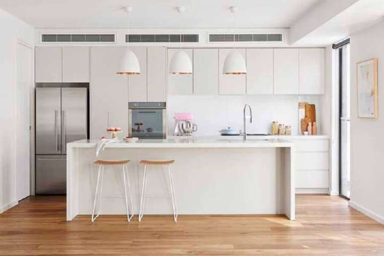 31. Decoração clean para cozinha grande planejada com ilha e pendentes brancos – Foto: Home Beautiful