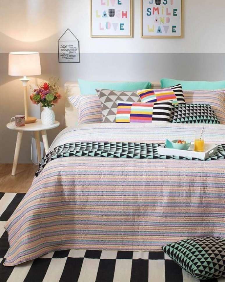 19. Mesa lateral de apoio para quarto decorado com parede pintada em duas cores e almofadas coloridas – Foto: Tok & Stok