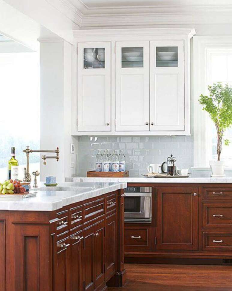 17. O armário de cozinha de madeira escura com tampo de granito branco encanta a decoração. Fonte: Pinterest