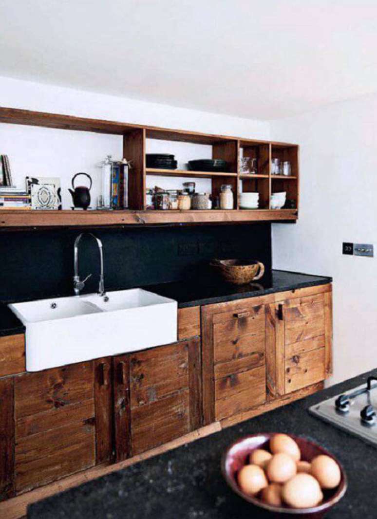 4. Armário de madeira maciça e bancada de granito preto complementam a decoração da cozinha. Fonte: Residence Style