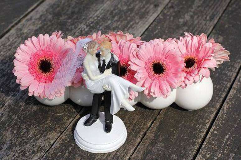 36. Decoração delicada de casamento com noivinhos e flores de gérbera rosa. Fonte: Pinterest