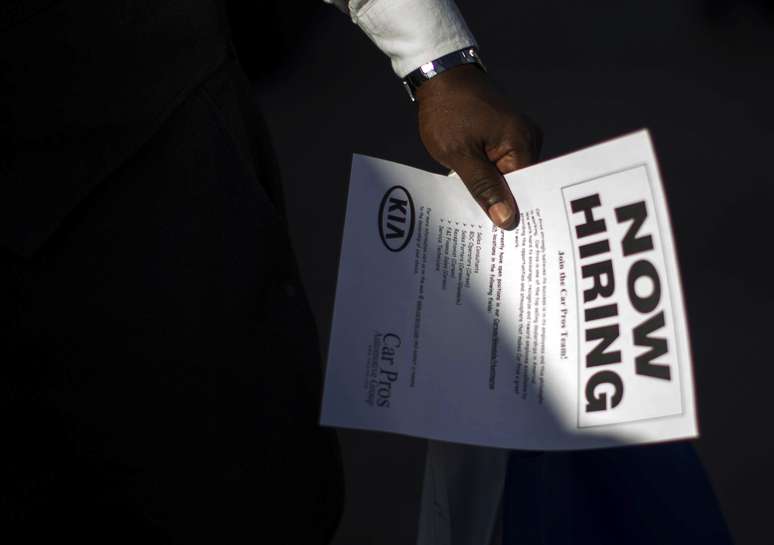 Desempregado segura panfleto com anúncio de vagas de trabalho, em Carson, na Califórnia 