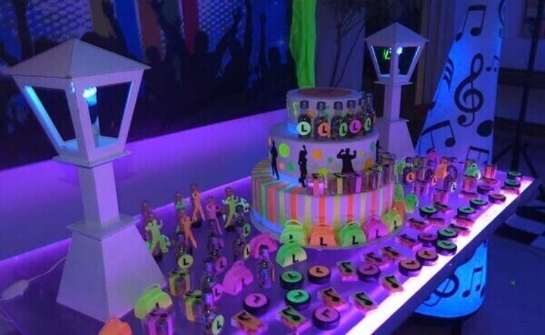 37. Em festa  neon simples, o bolo e as lanternas laterais ganham destaque na mesa.