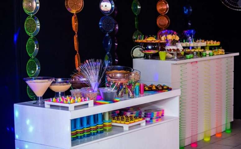 49. Mesas auxiliares ajudam na distribuição de doces e bebidas em festa neon. Foto: Pinterest