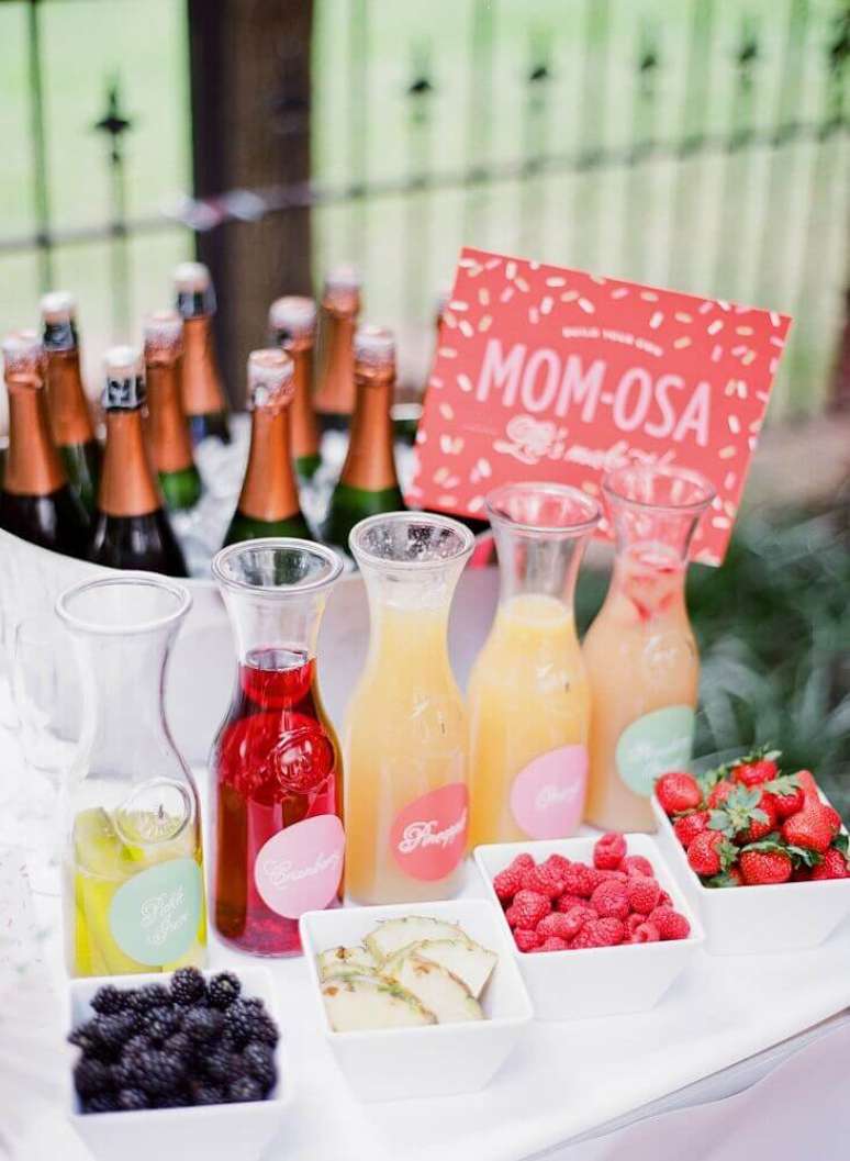 76. Uma mesa de bebidas e sucos fica bonita e criativa na decoração de chá de bebê, principalmente com frutas e champanhe – Foto: PartySlate