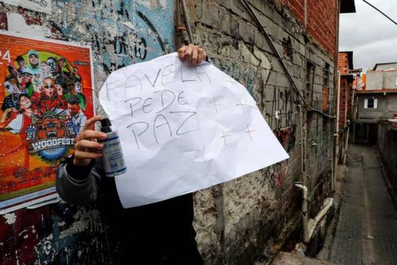 Morador de Paraisópolis segura cartaz pedindo paz