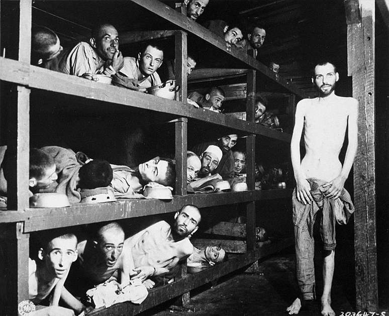 Trabalhadores escravizados em seus leitos no campo de concentração após a libertação em abril de 1945. Nesta foto, está Elie Wiesel, futuro vencedor do Nobel da Paz, sétimo a partir esquerda, na segunda fileira de beliches, junto à viga de madeira