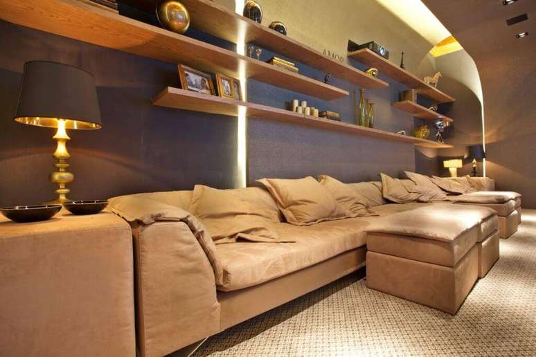 51. Cinema em casa conta a presen&ccedil;a de um sof&aacute; e diversas prateleiras. Projeto por Guardini Stancati.