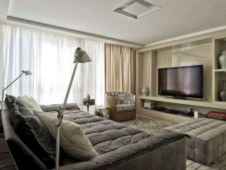 37. A sala de estar com TV grande pode ter sofá com assento largo para deixar a sessão cinema mais gostosa. Fonte: Pinterest