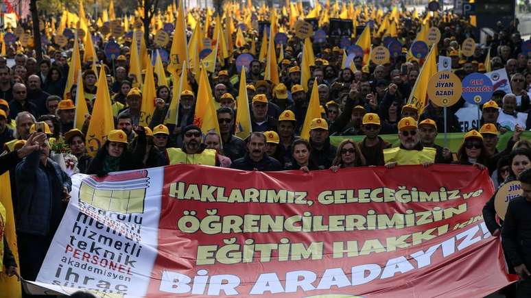 Professores e pesquisadores da Turquia protestam em Ancara, com cartaz dizendo: "Estamos juntos pelo direito de nossos estudantes à educação"