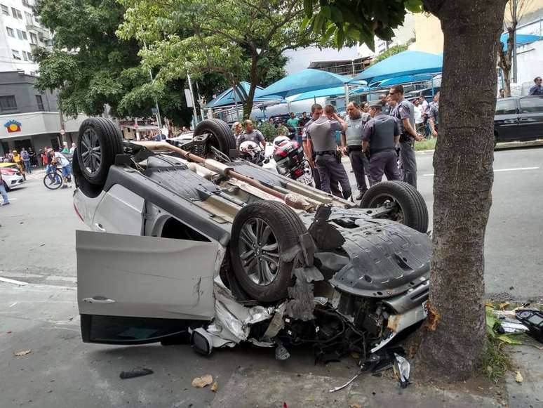 O carro roubado bate na lateral de outro veículo, capota, invade a calçada e para ao bater em uma árvore na Rua dos Pinheiros, em Pinheiros, zona oeste de São Paulo