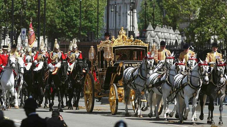 Grandes multidões vêm ver a rainha conduzida por carruagem durante a abertura do Parlamento