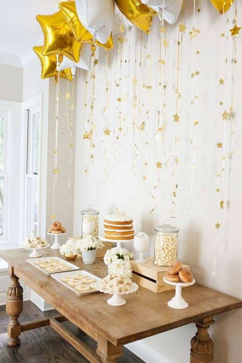 24. Ideia de festa de aniversário surpresa decorada com balões em formato de estrelas brancas e douradas – Foto: Pinterest