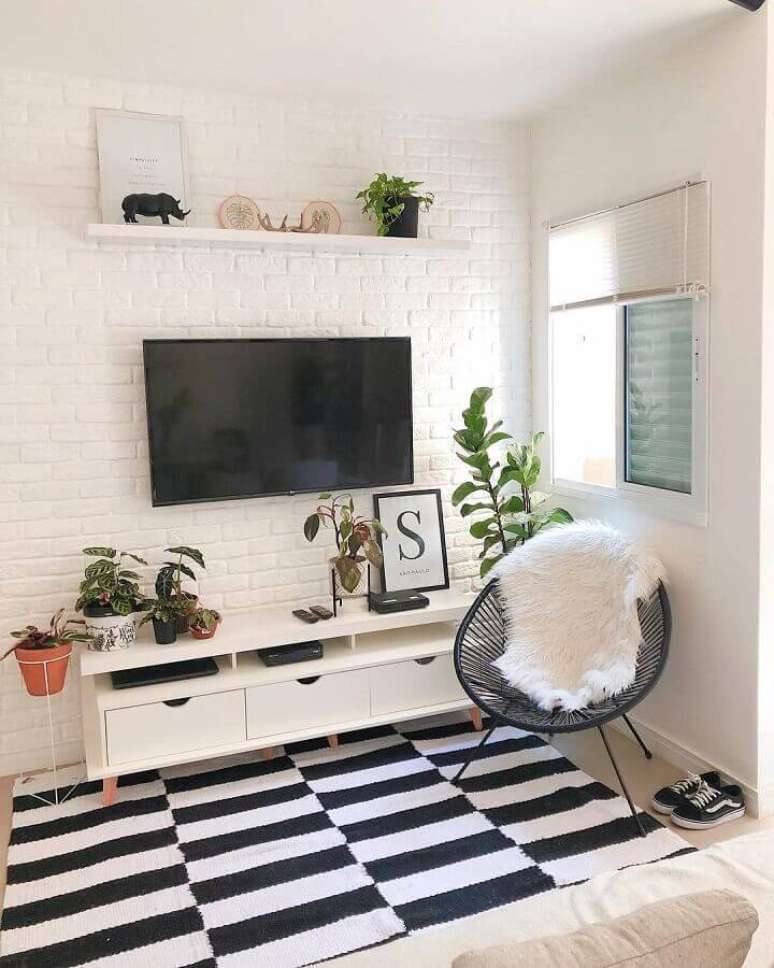 29. Cor branca para sala simples decorada com tapete preto e branco e parede de tijolinho branca – Foto: Casa Cobre