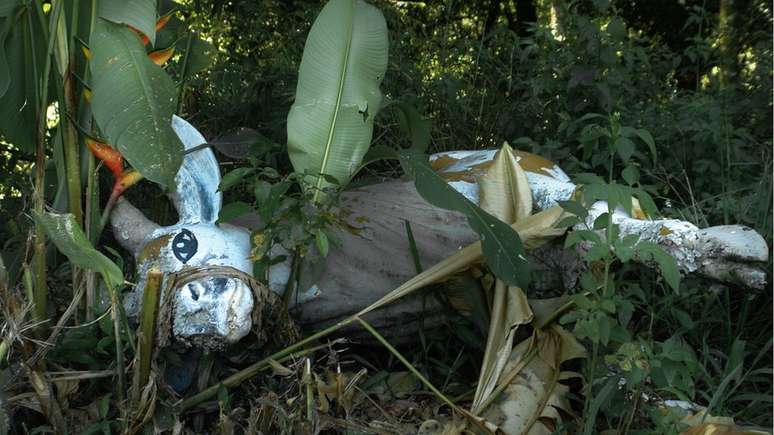 Alguns dos bonecos estão caídos e cobertos por mato e plantas