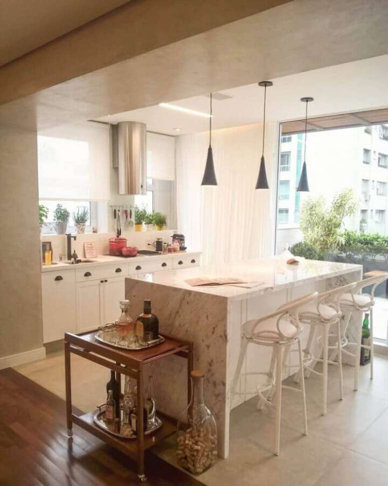 24. Cozinha pequena toda branca decorada com ilha de m&aacute;rmore branco e pendentes pretos &ndash; Foto: Arq. Alessandra Stevanato