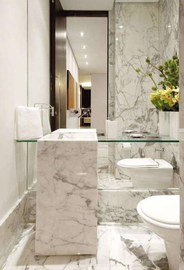 52. Lavabo sofisticado todo decorado com m&aacute;rmore branco Carrara e bancada de vidro &ndash; Foto: A Gente Decora