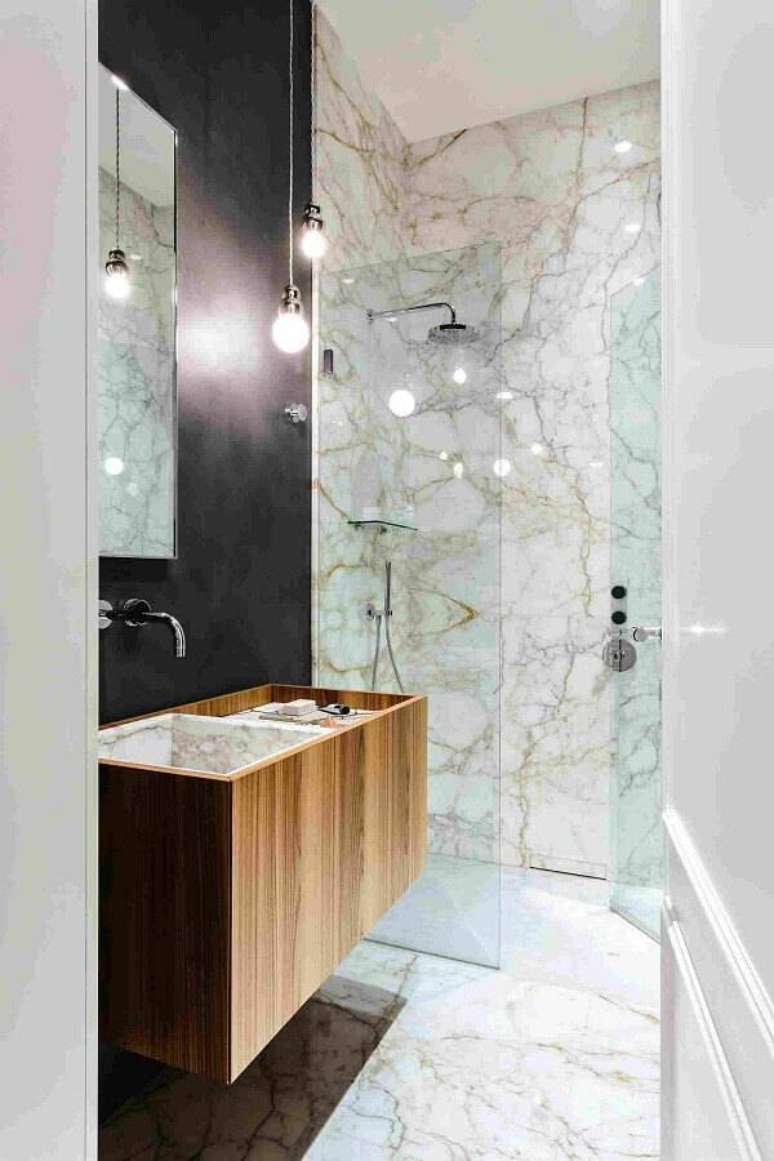 53. Banheiro decorado com mármore branco Paraná e gabinete de madeira – Foto: Decostore