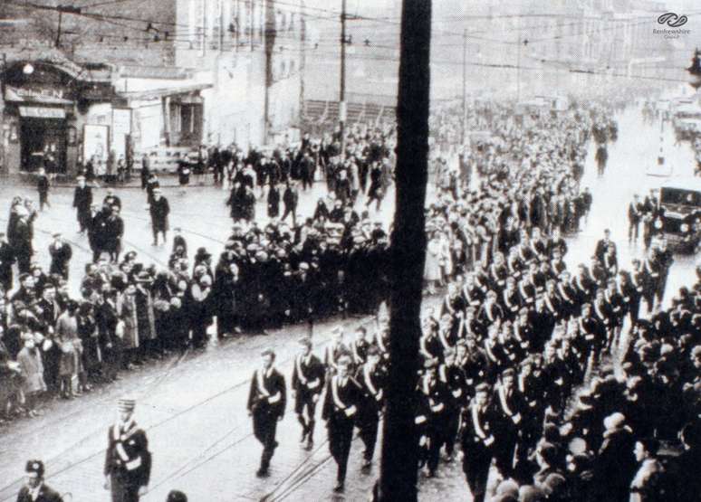 Grupo Boys Brigade marcha em frente ao cinema no funeral das vítimas