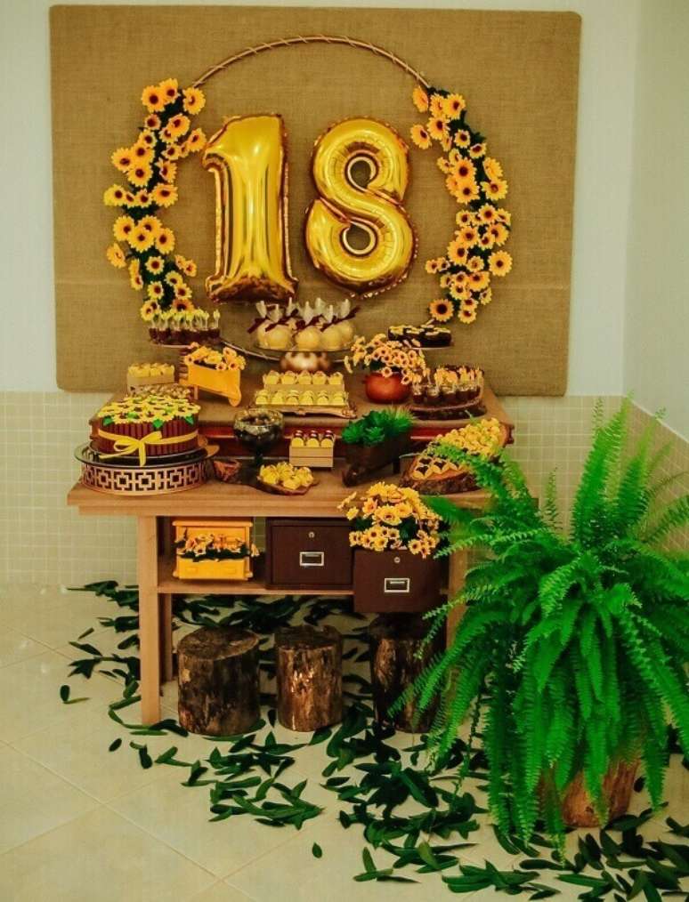 21. Mesa simples para festa tema girassol com mesa de madeira e flor de samambaia. Fonte: Pinterest