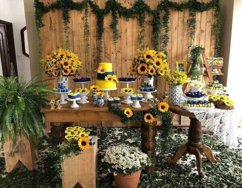 69. Decoração rústica para festa tema girassol com arranjos florais e painel de madeira. Fonte: Pinterest