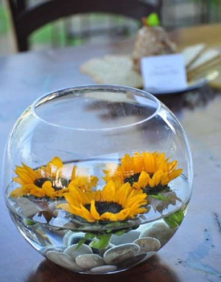 71. Utilize o vaso transparente com pedras, água e flores de girassol para decorar a mesa. Fonte: Pinterest