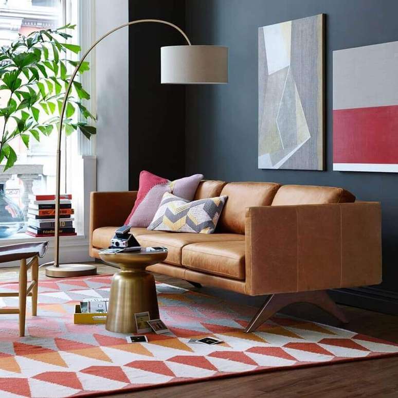 51. Modelo de sofá de couro com design moderno para sala com parede preta e tapete colorido – Foto: Assetproject