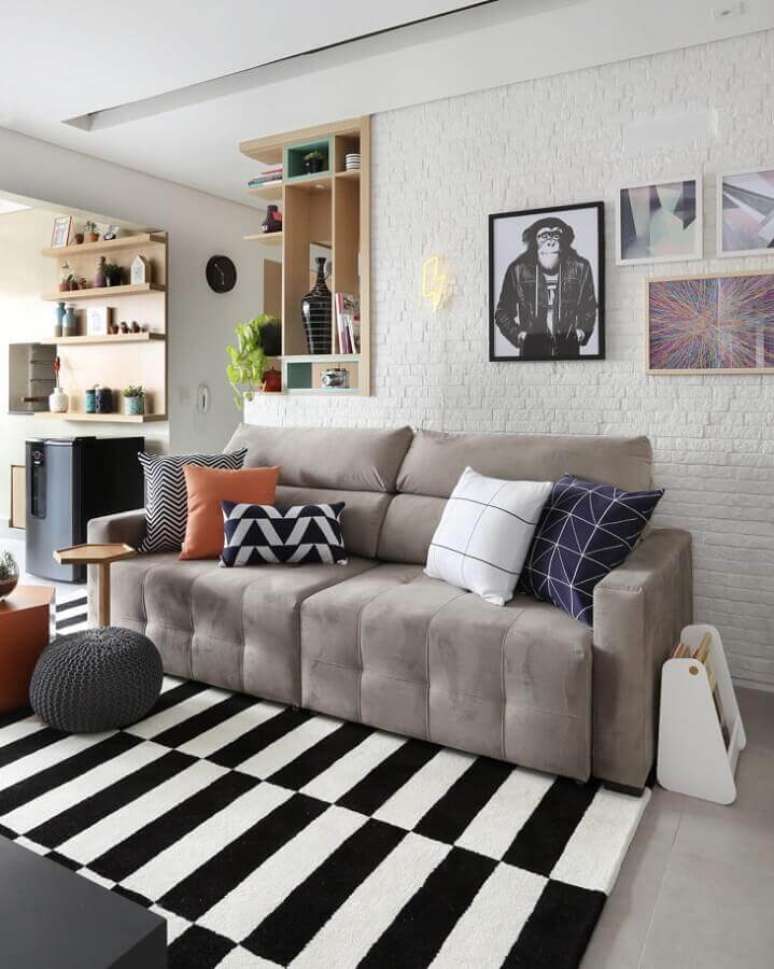 72. Sofá retrátil cinza para decoração de sala de estar com tapete preto e branco listrado e parede de tijolinho branca – Foto: Bianchi & Lima Arquitetura