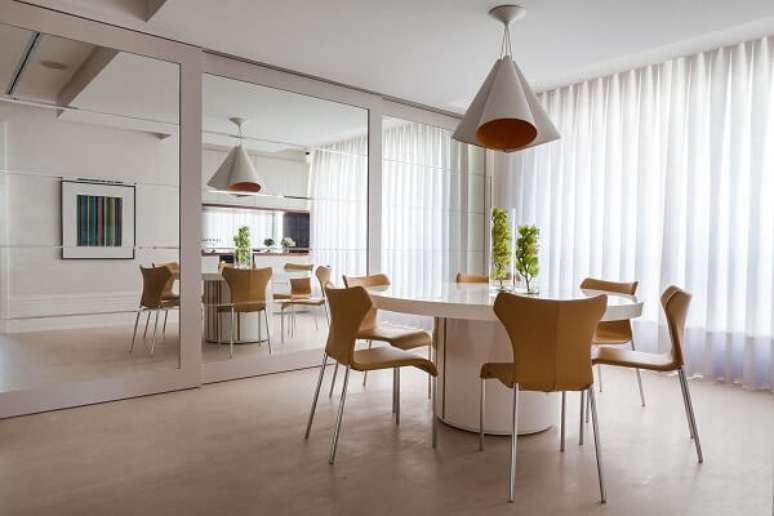 18. Ambiente espelhado com mesa de jantar redonda branca. Projeto por Olegário de Sá & Gilberto Cioni