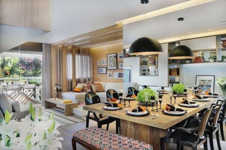 85. Ambiente integrado com mesa de jantar de madeira e cadeiras pretas. Projeto por Quitete & Faria