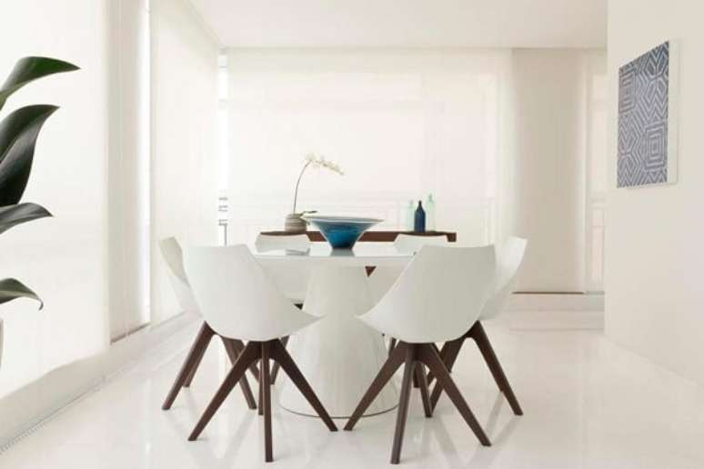 17. Mesa de jantar redonda branca se harmoniza com a decoração clean do ambiente. Projeto por Arthur Decor