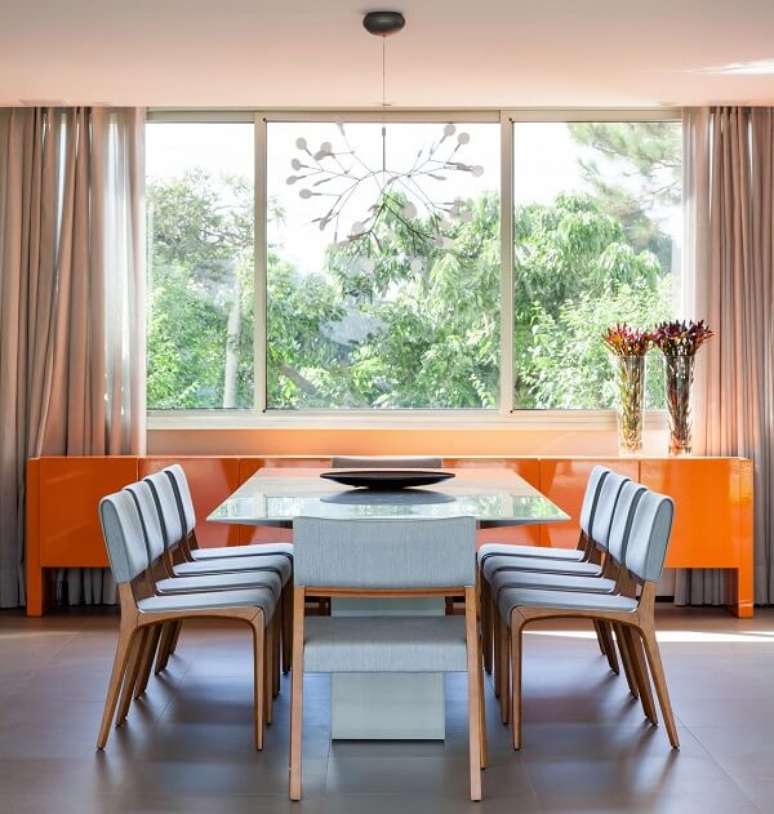 2. Mesa quadrada com tampo de vidro e aparador laranja. Projeto por Consuelo Jorge
