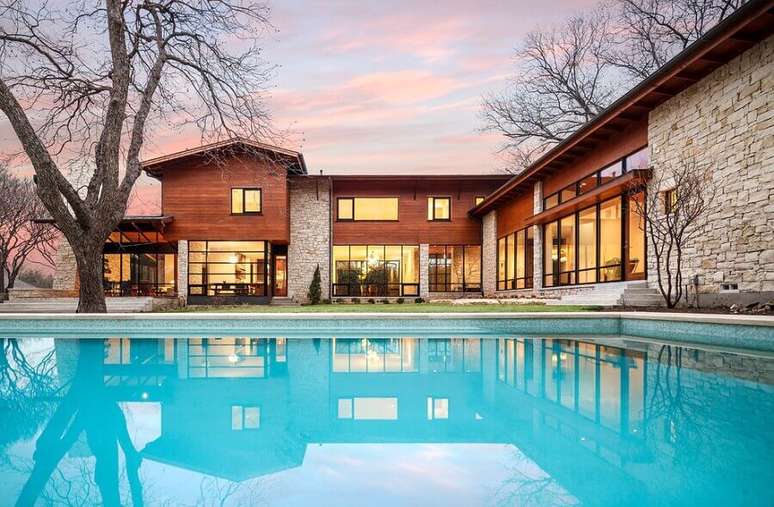 30. Lindo modelo de casa em L com piscina e com revestimento de pedra e madeira – Foto: Pinterest