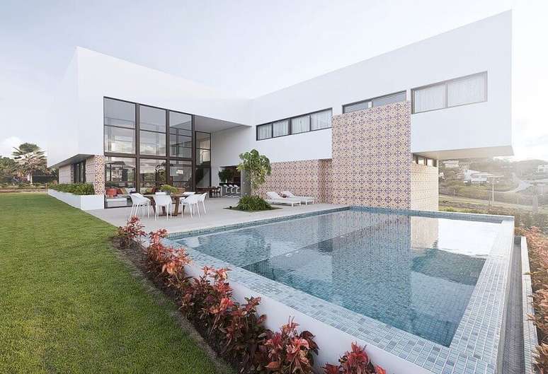 33. Casa em L com piscina e parede de vidro para ajudar na iluminação – Foto: Santos e Santos Arquitetura