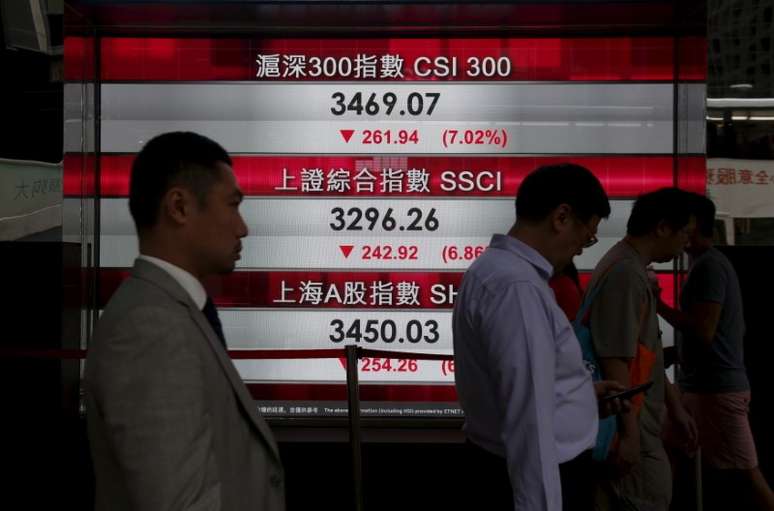 Pessoas passam por painel com índices do mercado acionário chinês em Hong Kong.   REUTERS/Bobby Yip