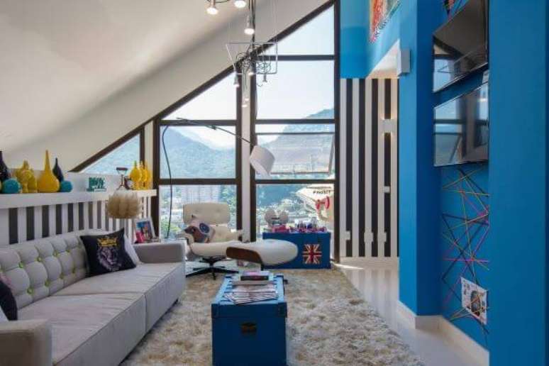 55. Sala de estar com parede azul e iluminada com janela de vidro – Foto: Mmpm